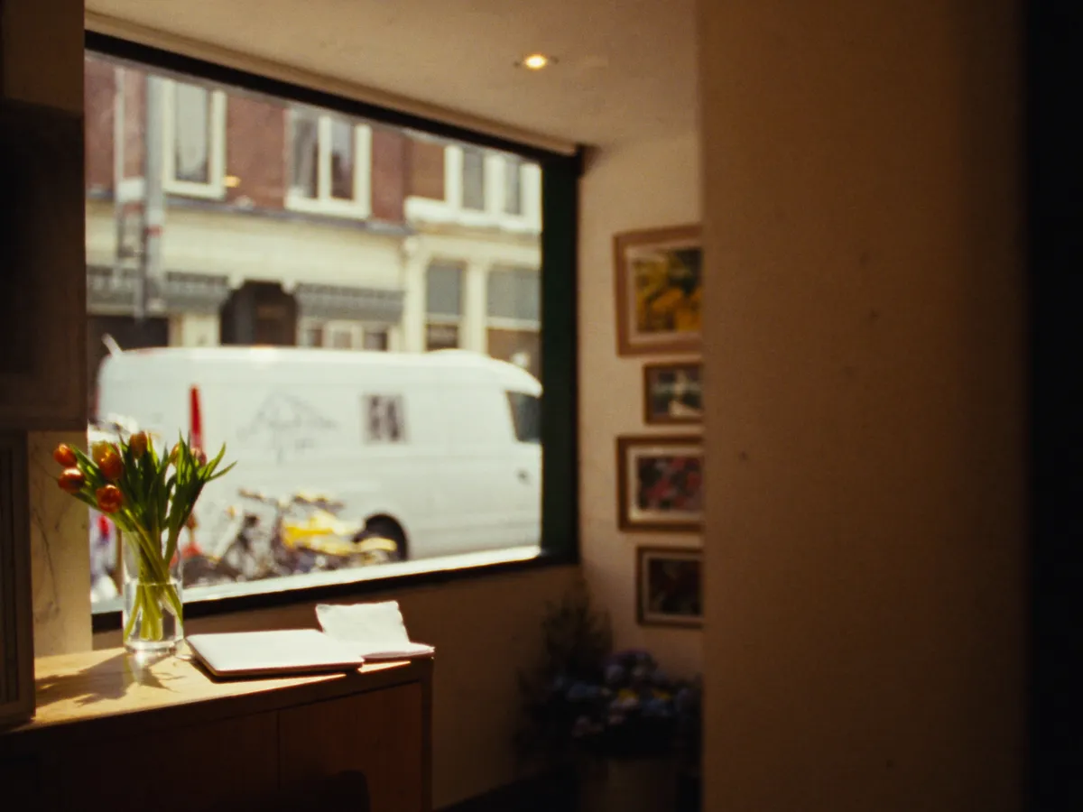 Zonnige winkel met houten toonbank, laptop en verse tulpen.